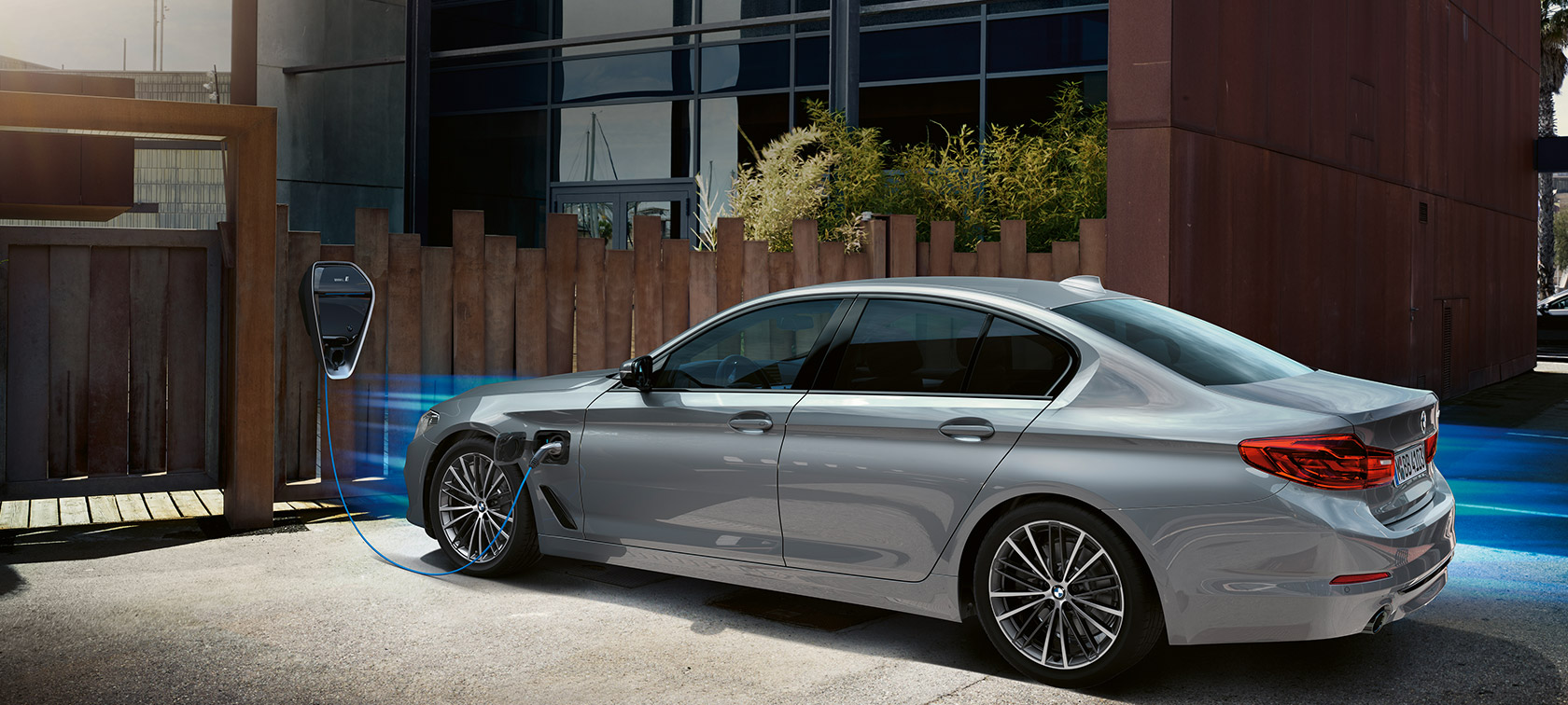 BMW 530e до зарядна станция. BMW 530e, три четвърти изглед отзад до зарядна станция.