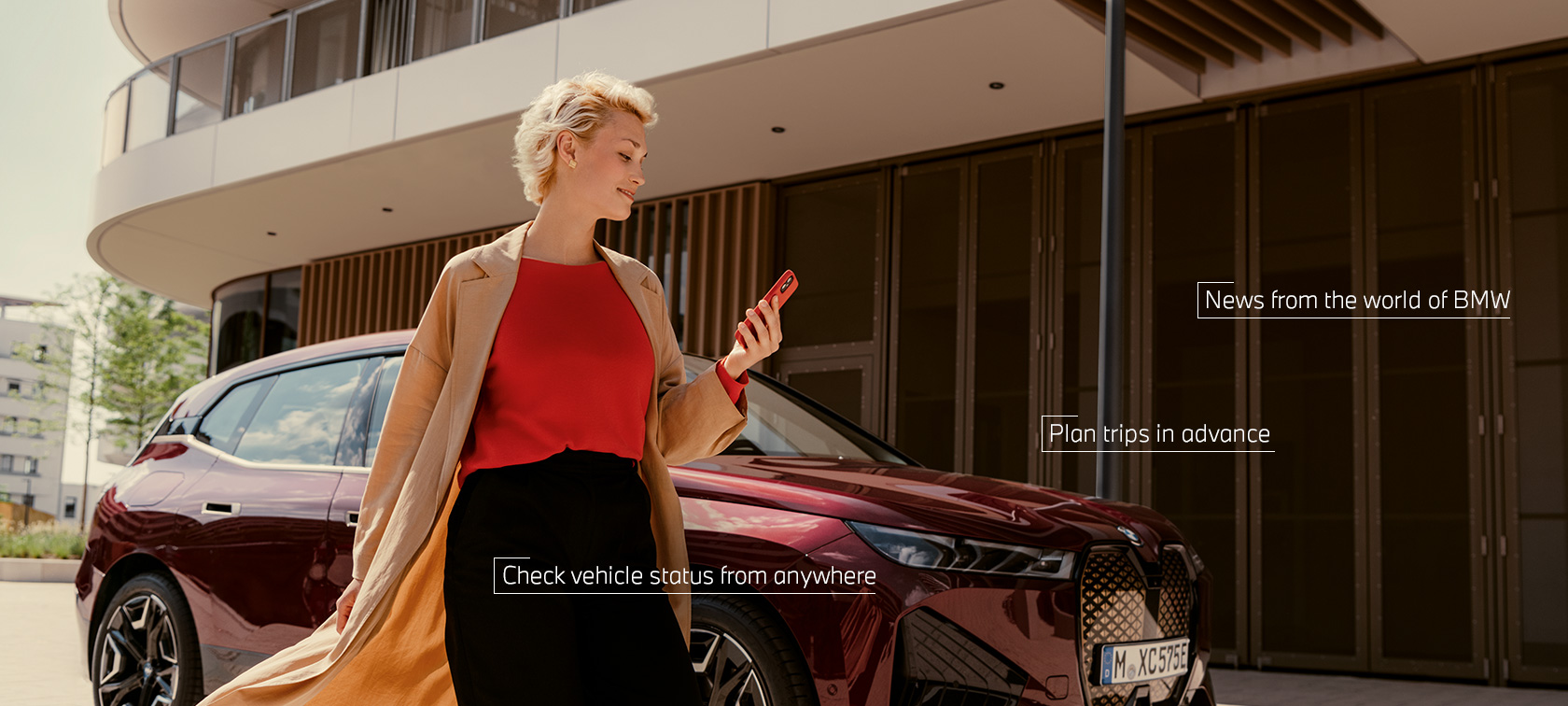 Жена пред BWW iX ползва My BMW App на смартфон Жена пред BWW iX ползва My BMW App на смартфон