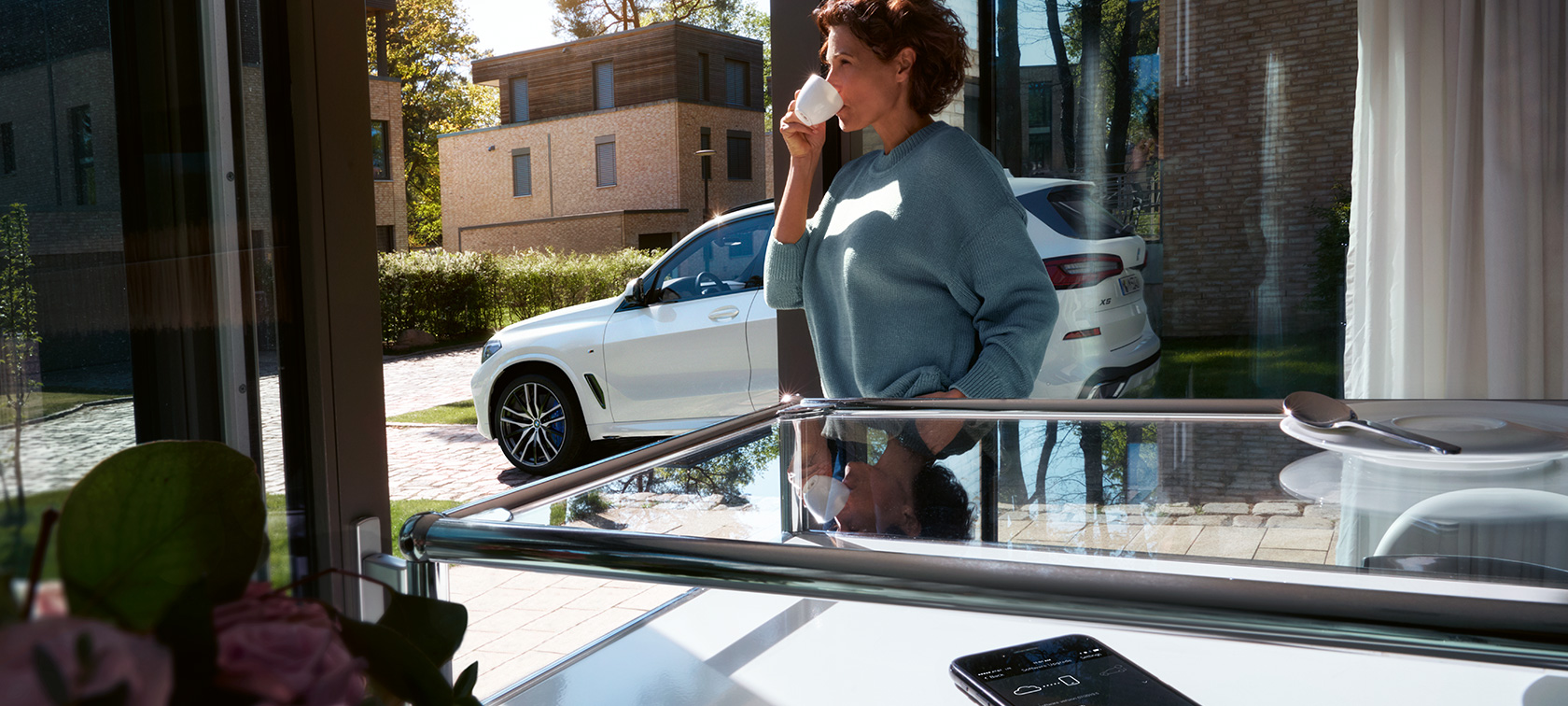 BMW Remote Software Upgrade Жена пие от чаша, докато BMW Remote Software Upgrade актуализира софтуера на нейното BMW X5