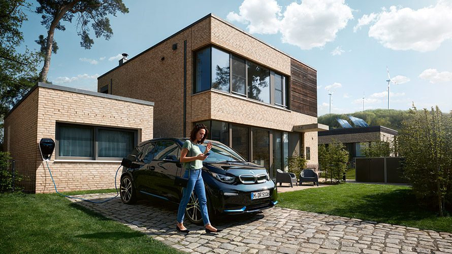 Digital Charging Service Жена стои пред BMW i3 и ползва Digital Charging Service на смартфона си