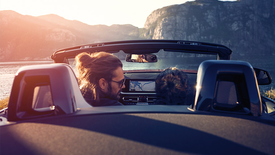Мъж и жена седят в BMW на фона на езеро и планински пейзаж BMW Финансови услуги BMW Лизинг Мъж и жена седят в BMW на фона на езеро и планински пейзаж