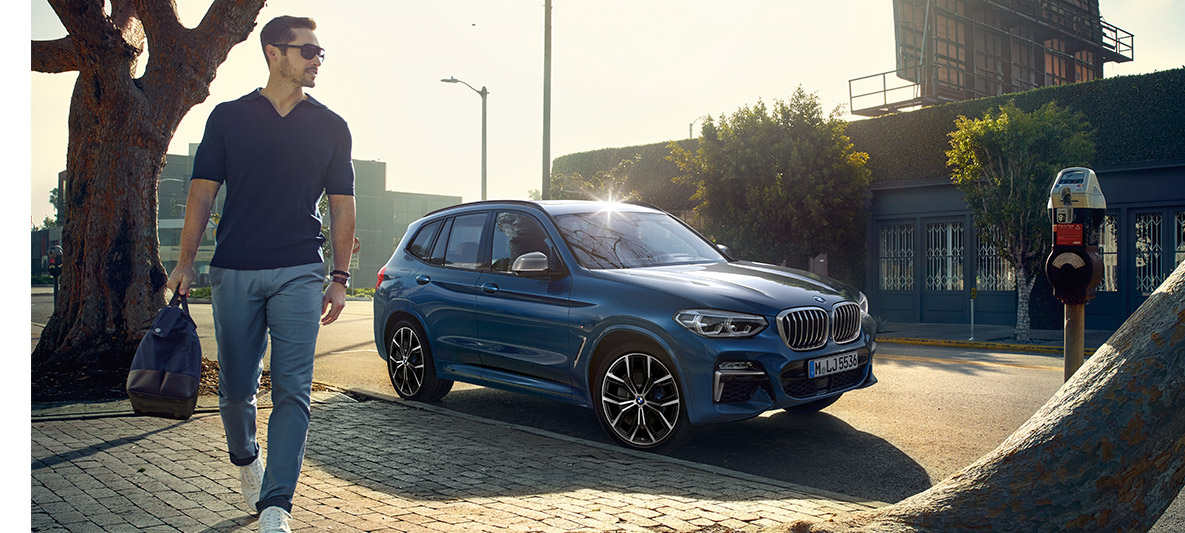 Мъж със слънчеви очила пред синьо BMW Мъж със слънчеви очила пред синьо BMW