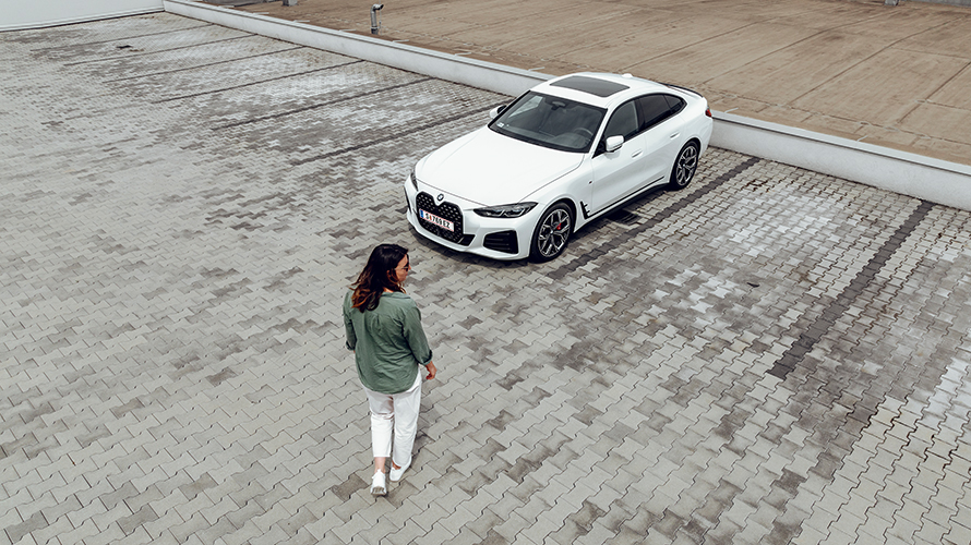Жена върви към BMW i4, но гледа надясно. Жена върви към BMW i4, но гледа надясно.