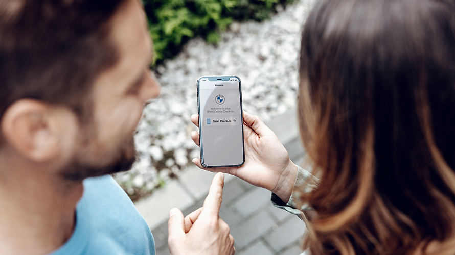 Човек сочи към екрана на смартфона. Логото на BMW е на екрана. Човек сочи към екрана на смартфона. Логото на BMW е на екрана.