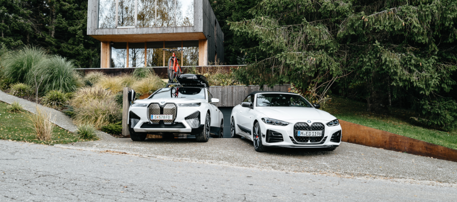 BMW iX с аксесоари и BMW M440i пред модерна къща. BMW iX с аксесоари и BMW M440i пред модерна къща.